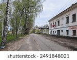 Old bumpy paved road through the city, desolation, empty streets and old outbuildings. Tutaev town in spring season, Yaroslavl region, Russia.