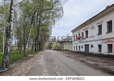Old bumpy paved road through the city, desolation, empty streets and old outbuildings. Tutaev town in spring season, Yaroslavl region, Russia.