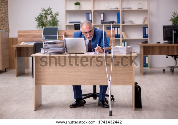 Old businessman employee after accident working in\
the office