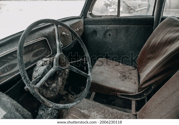 Old cabin of a rusty\
abandoned truck. Steering wheel and dashboard. Forgotten and\
abandoned car.