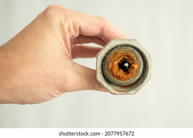 Old Calcified And Clogged Water Pipe With Brown Rust Held In Hand By Plumber