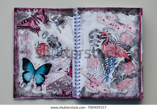 An old calendar has been made into an art\
journal. It is used to test and practice different techniques. A\
spread is open with mixed media art\
work.