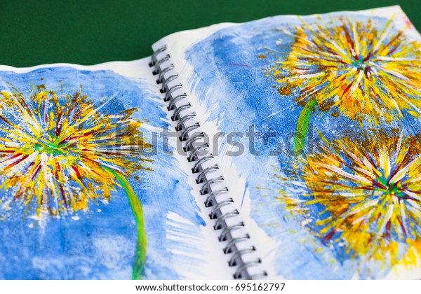 An old\
calender with spiral binding has been made into an art journal for\
mixed media art. It is used for experimenting with different media\
and techniques. Acrylic painting of\
flowers.