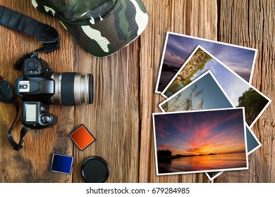 Old camera, cap, memory cards  and stack of photos on vintage wooden background, photography hobby lifestyle concept