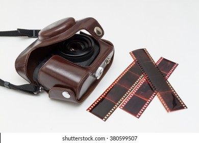 old camera in open case and blank film strip on white background