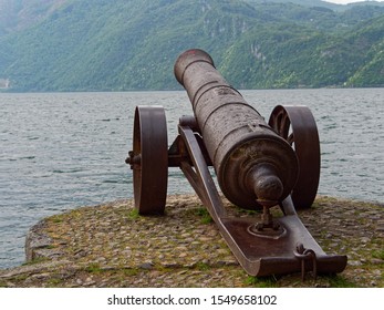 Old Cannon Aiming Towards The Lake On The Shore Of Lake Como In Italy.