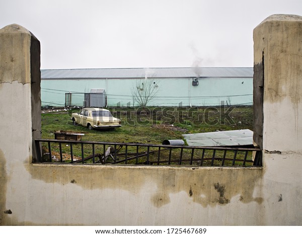 Old car\
behind the fence. Yellow color.\
Russia.
