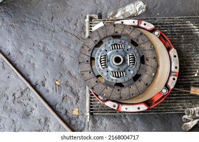 Old Car Brake Disc On Dirty Garage Floor, Damaged Car Spare Part, Car Service And Maintenance Concept