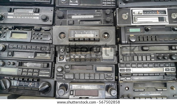 Old, car cassette radios stacked on top of\
each other on the shelves in car\
service.