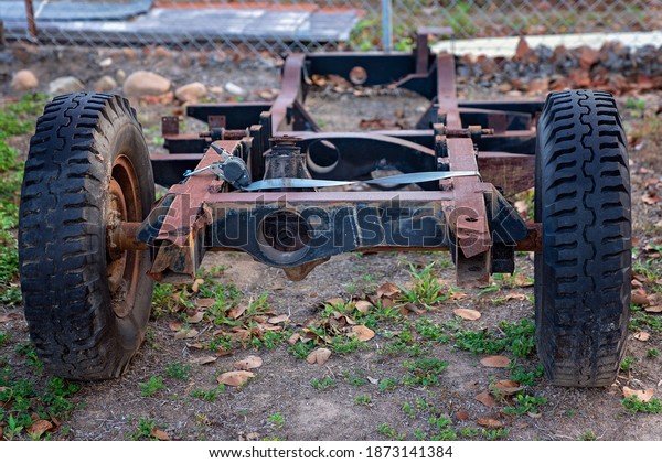 An old car\
chassis discarded in a rural\
backyard