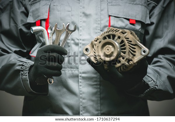 Old car electric generator and wrenches in the car\
mechanic hands close up.