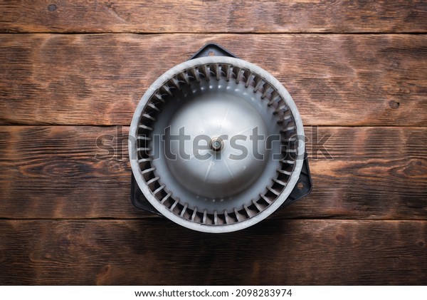 Old car fan heater\
motor replacement concept. Car fan heater on the wooden workbench\
flat lay background.