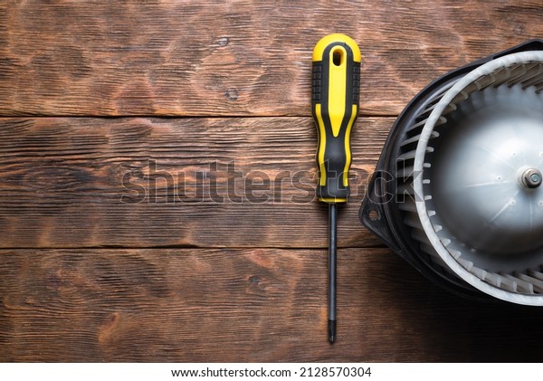 Old car fan heater\
motor replacement concept. Car fan heater on the wooden workbench\
flat lay background.