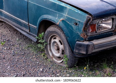 Old Car With Rust On The Body And Deflated Wheels. 