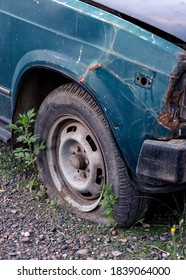 Old Car With Rust On The Body And Deflated Wheels. 