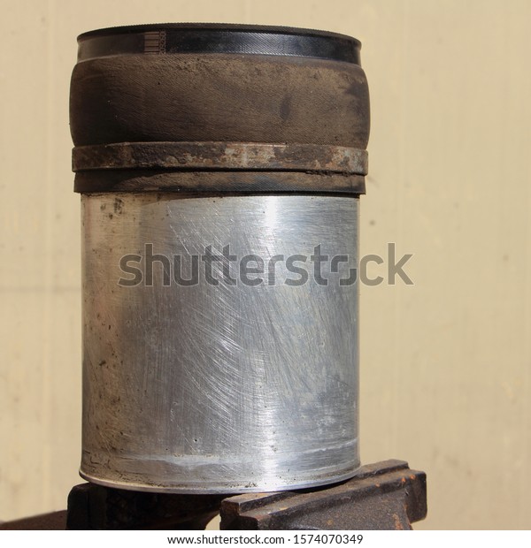 Old car\
shock absorber air cylinder on locksmith vise close up, pneumatic\
car suspension service repair\
rebuiding