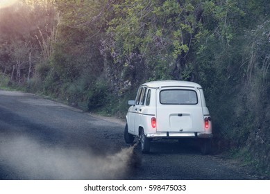 Old Car Standing At Side Of A Road With Engine Running And Thick Smoke Coming From Exhaust Pipe