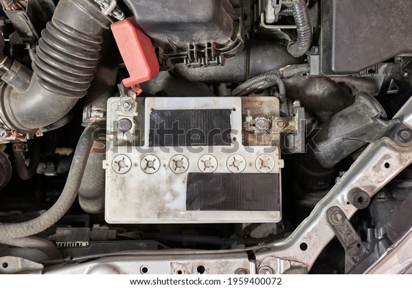 Old car starter battery inside the engine bay viewed\
from above top down