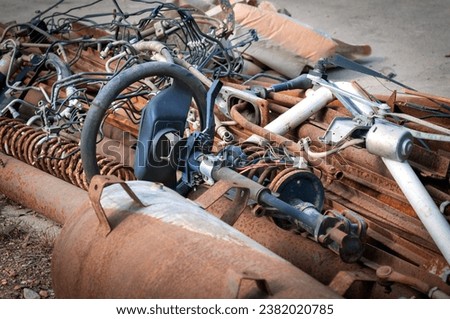 An old car steering wheel lies in a pile of rusty scrap metal. Car recycling concept. Close up. No people.