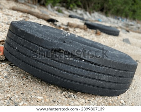 Old car tires on the beach, Water and sea coast pollution car tires on sand beach,An image of an old car tire ingrown into the sand, Old car tires with seaweed stuck on, selective focus.