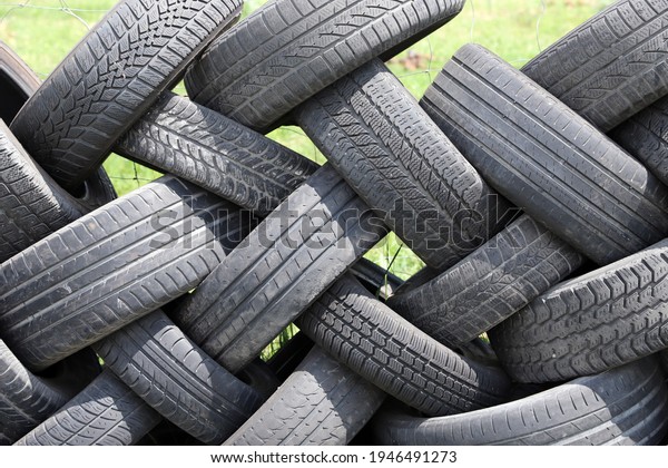 Old car\
tires in row as a fence  in a rural courtyard. Old tires functions\
as a protective fence. Household waste. Environmental disaster. \
Old tires as garbage on the\
ground