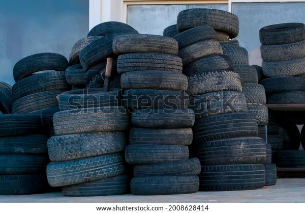 A lot of old car tires. Old tires are in a\
warehouse on the street.