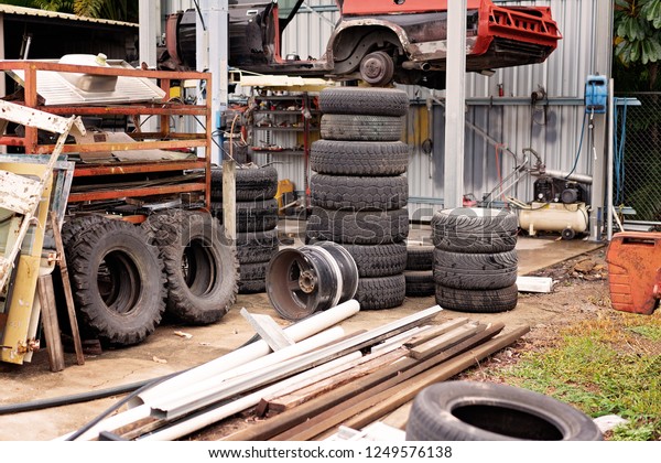 Old car tyre pile in a junk yard with other\
pieces of discarded\
equipment