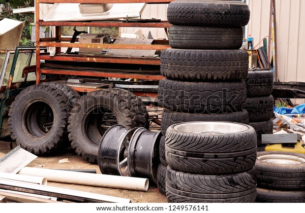 Old car tyre pile in a junk yard with other\
pieces of rubbish