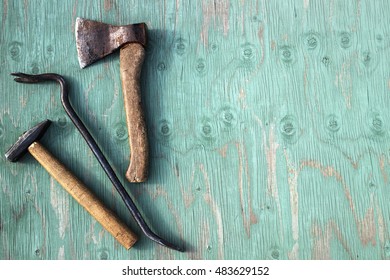 The old carpenter tools used. Axe, hammer and crowbar on green wooden background.