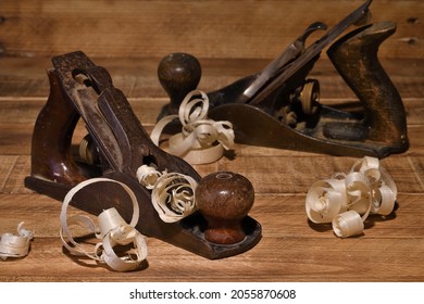 Old carpenter wood planes on burnt wood background with curved wood shaving. Hand woodworking tools - Shutterstock ID 2055870608