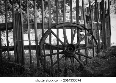 An old carriage wheel leaned on wooden fence