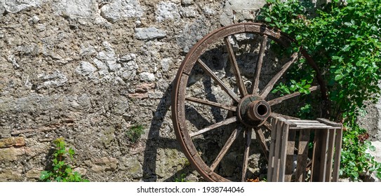 Old cartwheel in front of stone wall - rural background