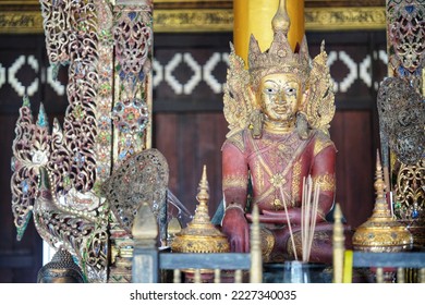 
An old carved wooden figure according to the beliefs of northern Thai people, golden face, red skin, decorated in ancient style. Worship on the wooden altar
