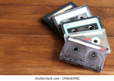 Old cassettes for a cassette tape recorder on a wooden background.