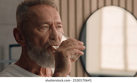 Old Caucasian man senior mature retired male in bath bathroom morning drinking still water drink holding glass refreshing healthy habit aqua balance h2o refresh thirst health care elderly generation - Powered by Shutterstock