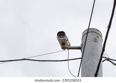 old CCTV surveillance camera on rusted pole at overcast day, closeup