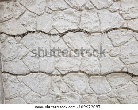 Old cement fence with geometric relief, painted with dark gray paint. Abstract background.