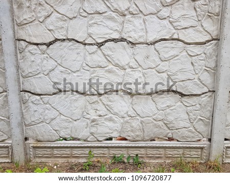 Old cement fence with geometric relief, painted with dark gray paint. Abstract background.