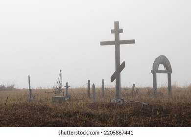 Old Cemetery In The Countryside. Large Wooden Cross And Graves In The Tundra. Foggy Autumn Weather. Surroundings Of The Abandoned Village Novostroyka, Magadan Region, Siberia, Russia. Sad Mood.