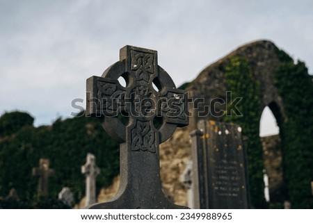Old Cemetery in Ireland with Celtic Cross Gravestones and Old Church in Background