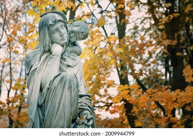 Old Cemetery Monument Of Sad Mother And Baby Angel, Autumn Background. Beautiful Grieving Woman Gravestone. Concept Of Mourning, Condolence, Remember, Mourn, Memory. All Saints Day, All Souls Day