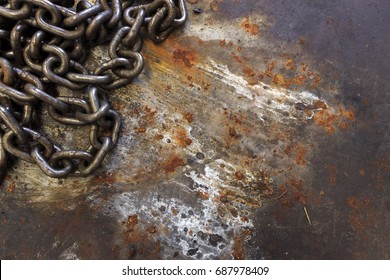 old chain on rusted metal sheet with soft-focus and over light in the background