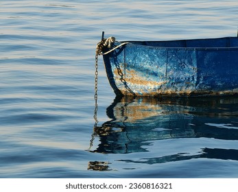 Old,  chained blue rusty fishing boat in the lake. Reflection in the water. Sunny day. Floating, concept. - Powered by Shutterstock