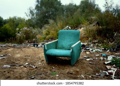The old chair is in a landfill. Abandoned wasteland with waste and garbage.
