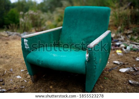 The old chair is in a landfill. Abandoned wasteland with waste and garbage.