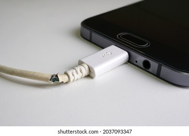 Old charger cable broken and smartphone, Defective charging cord, Connection deterioration device