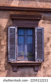 An old and charming window with blue shutters in a traditional building. The window is surrounded by a painted wall, letting in natural light and giving a glimpse into the history of the building - Shutterstock ID 2255112211