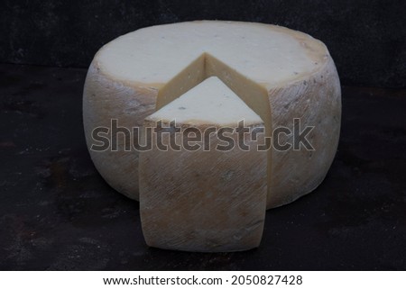 Old cheddar cheese. Wheel aged cheese. Aged cheddar cheese wheel on dark wooden floor.