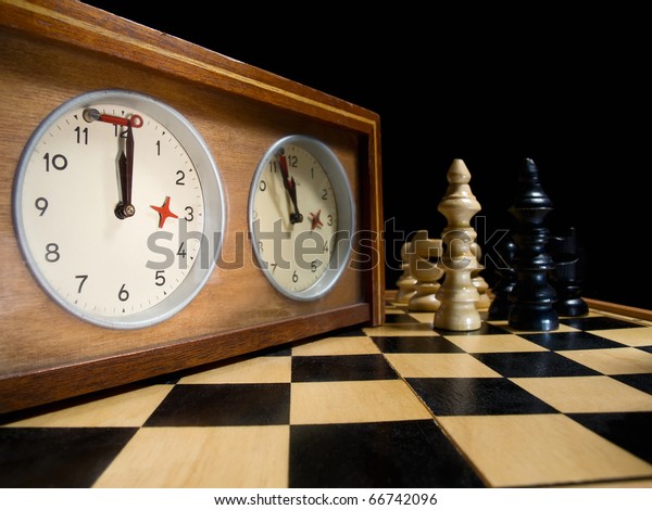 old chess clock on the\
chessboard with figures ,flag in position which indicates  running\
out of time