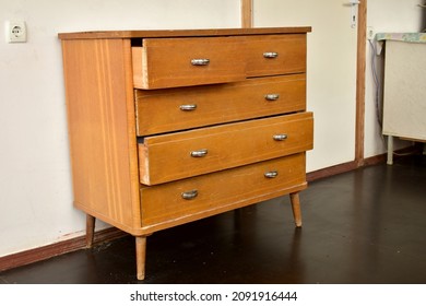 An old chest of drawers with shiny metal handles stands in the room. - Shutterstock ID 2091916444